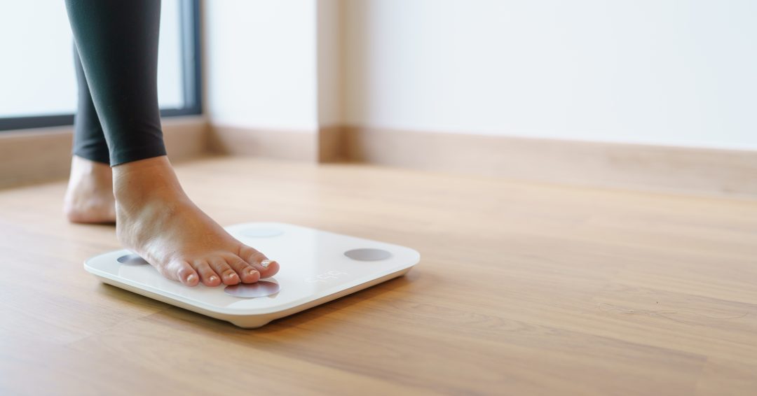 Lose weight. Fat diet and scale feet standing on electronic scales for weight control. Measurement instrument in kilogram for diet
